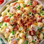 Creamy beef ranch pasta salad in a large white bowl with seasoned ground beef, cherry tomatoes, and cheddar cheese