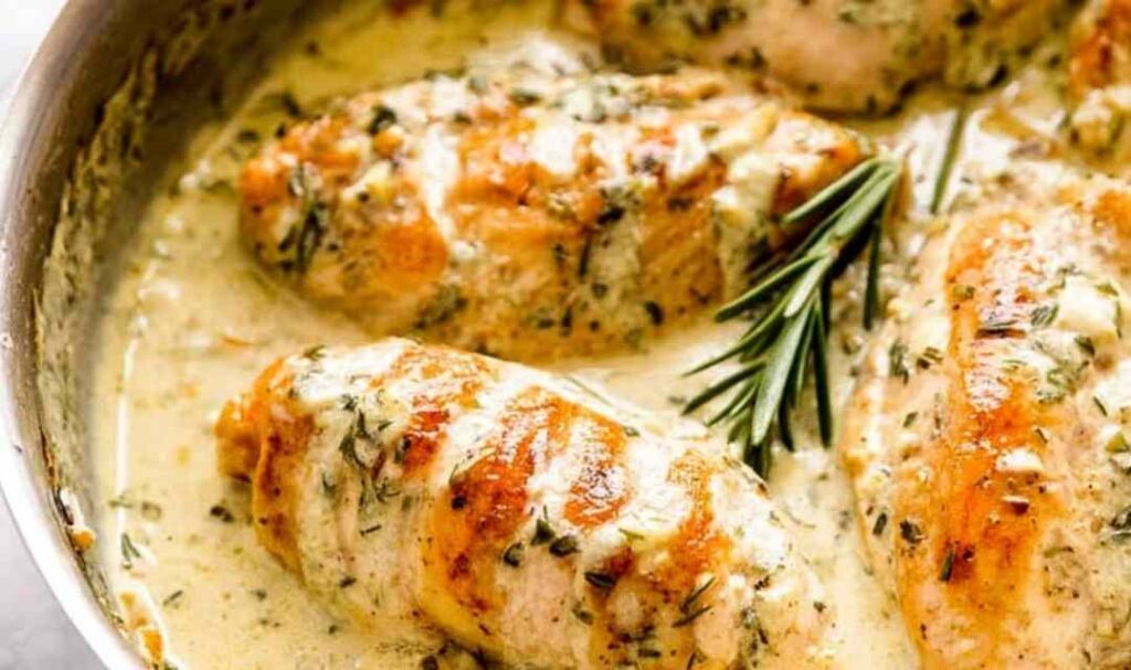 Creamy rosemary chicken breasts in a skillet with herb cream sauce