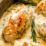 Creamy rosemary chicken breasts in a skillet with herb cream sauce