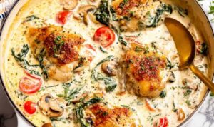 Creamy Tuscan chicken in a skillet with spinach, cherry tomatoes, and parmesan cream sauce