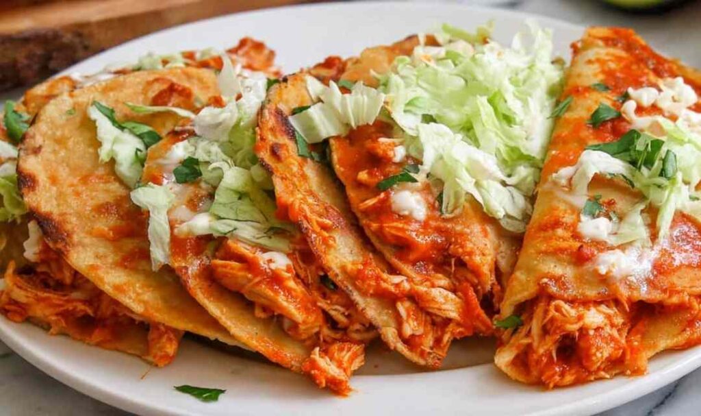 Crispy baked chicken tacos on a parchment-lined sheet pan with golden crunchy corn shells and melted cheese
