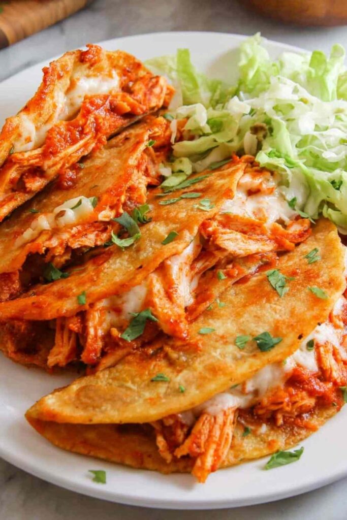 Crispy baked chicken tacos on a parchment-lined sheet pan with golden crunchy corn shells and melted cheese