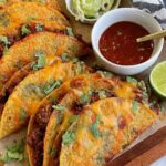 Crispy baked tacos on a baking sheet fresh from the oven, golden and filled with seasoned ground beef and melted cheese