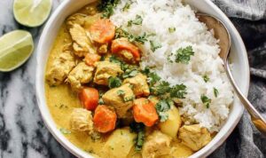 Crockpot Curry Chicken (Yellow Coconut Milk Slow Cooker Curry) Crockpot curry chicken served over basmati rice in a white bowl topped with fresh cilantro and chopped cashews