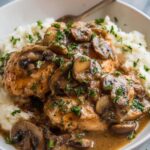 Crockpot chicken marsala with golden chicken thighs and mushrooms in a rich Marsala wine cream sauce served over mashed potatoes