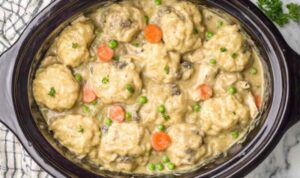 Crockpot chicken and dumplings with fluffy biscuit dumplings in creamy herb broth served in a deep bowl
