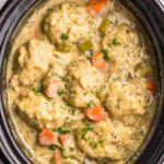 Crockpot chicken and dumplings with fluffy biscuit dumplings in creamy herb broth served in a deep bowl