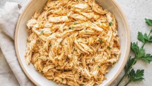 Crockpot shredded chicken breast in a slow cooker with seasoned broth