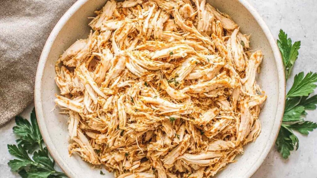 Crockpot shredded chicken breast in a slow cooker with seasoned broth