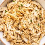 Crockpot shredded chicken breast in a slow cooker with seasoned broth