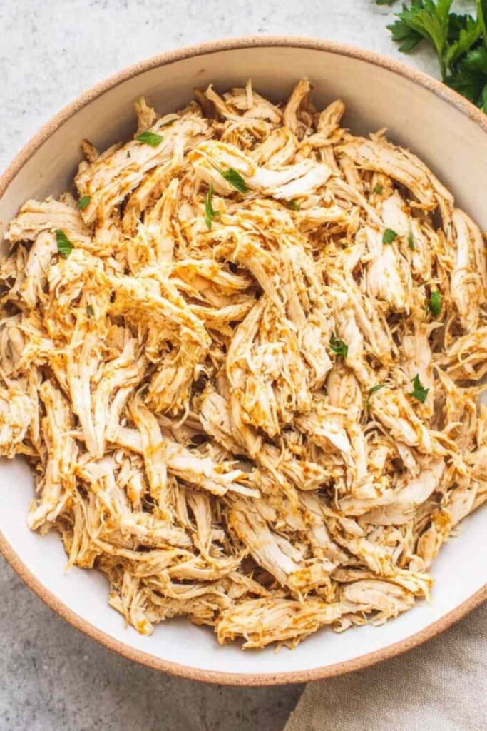 Crockpot shredded chicken breast in a slow cooker with seasoned broth