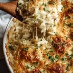 French onion chicken rice bake in a white baking dish with melted Gruyere cheese and fresh parsley