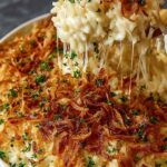 French onion chicken rice bake in a white 9x13 baking dish with melted Gruyere cheese and golden caramelized onions