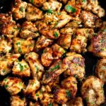 Garlic butter chicken bites in a cast iron skillet with fresh parsley and golden crust