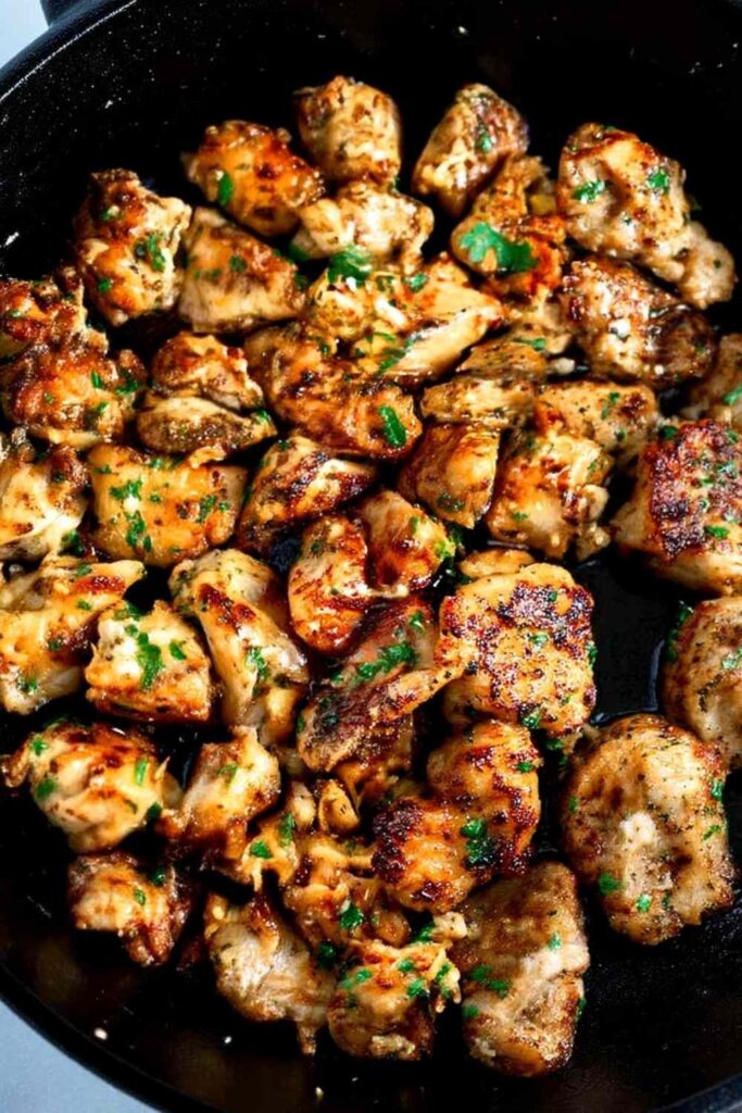 Garlic butter chicken bites in a cast iron skillet with fresh parsley and golden crust