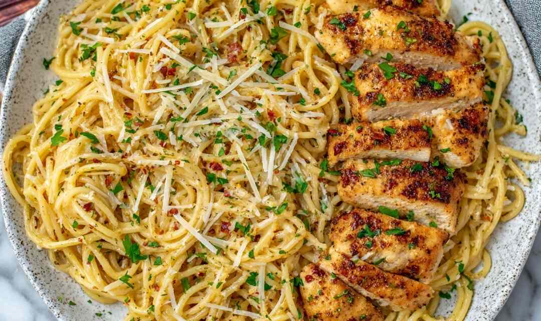 Garlic butter chicken pasta in a skillet with creamy Parmesan sauce and fresh parsley garnish