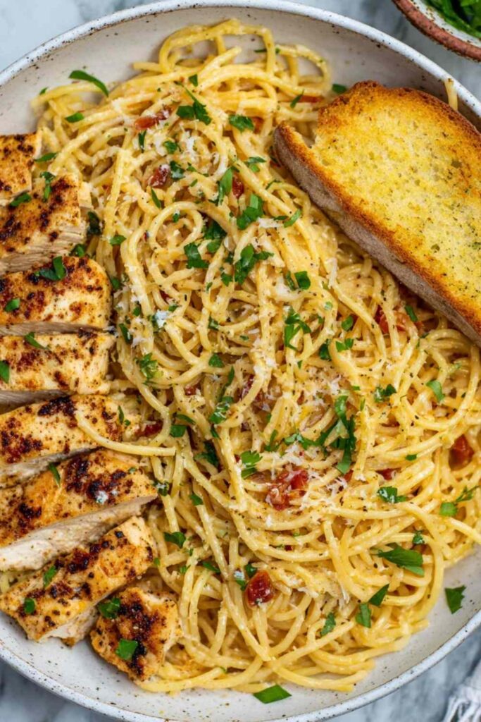 Garlic butter chicken pasta in a skillet with creamy Parmesan sauce and fresh parsley garnish
