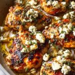Greek chicken with lemon and feta baked in a white dish topped with crumbled feta and fresh dill