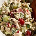 Greek tzatziki chicken salad in a white bowl topped with fresh dill and chopped almonds
