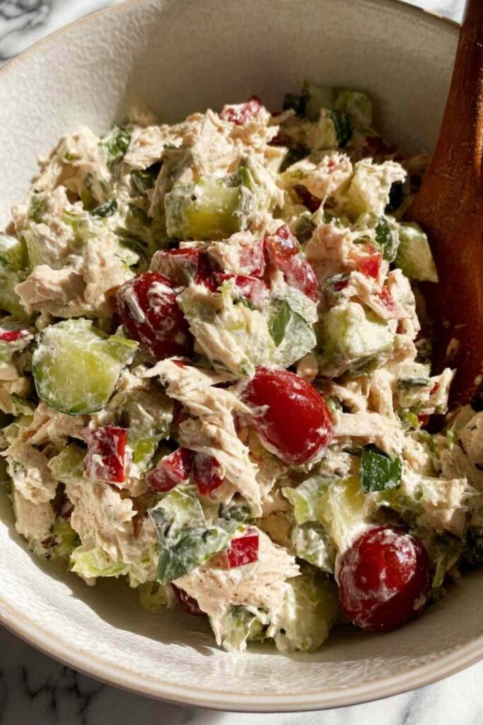 Greek tzatziki chicken salad in a white bowl topped with fresh dill and chopped almonds