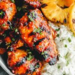 Grilled huli huli chicken recipe served with grilled pineapple and green onion garnish on a plate