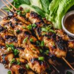 Grilled Vietnamese chicken thighs with lemongrass honey glaze, garnished with fresh cilantro and lime wedges on a white plate