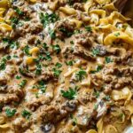 Creamy ground turkey stroganoff served over egg noodles garnished with fresh parsley in a white bowl