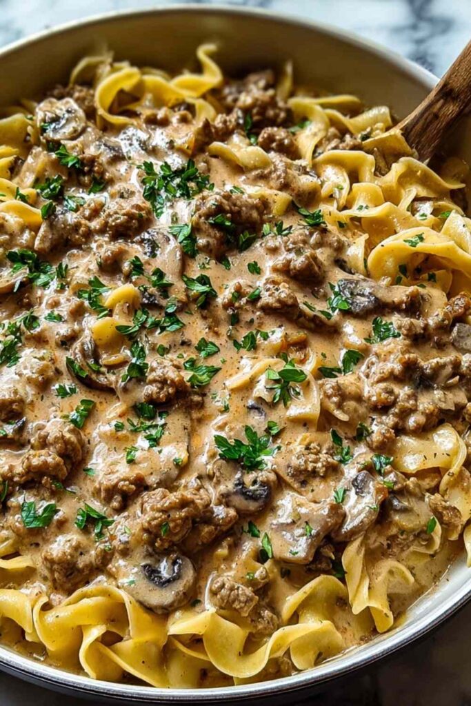 Creamy ground turkey stroganoff served over egg noodles garnished with fresh parsley in a white bowl