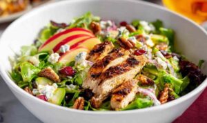 Fall harvest chicken salad with grilled chicken, apple slices, pecans, cranberries, and maple Dijon dressing in a white bowl