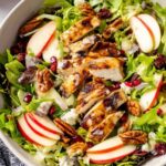 Fall harvest chicken salad with grilled chicken, apple slices, pecans, cranberries, and maple Dijon dressing in a white bowl
