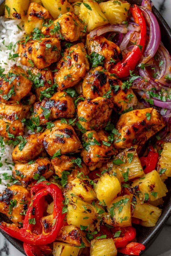 Hawaiian chicken sheet pan with caramelized pineapple chunks, red and yellow bell peppers, and teriyaki glaze on a parchment-lined baking sheet