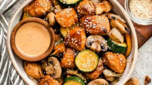 Hibachi chicken and vegetables in a skillet with golden seared chicken breast pieces, zucchini, mushrooms, carrots, and onion