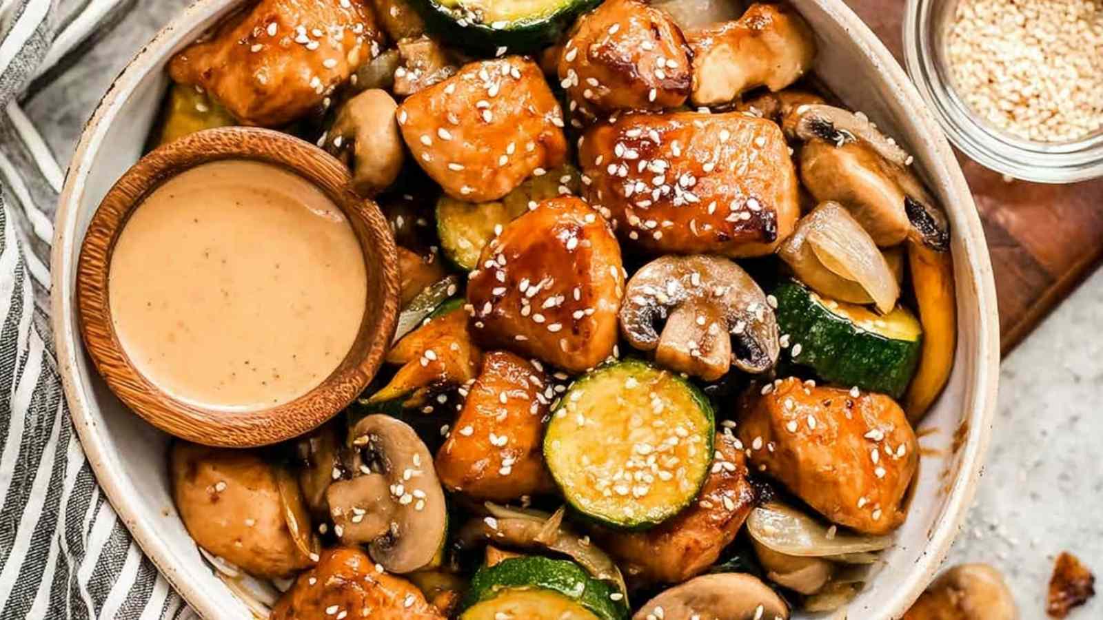 Hibachi chicken and vegetables in a skillet with golden seared chicken breast pieces, zucchini, mushrooms, carrots, and onion