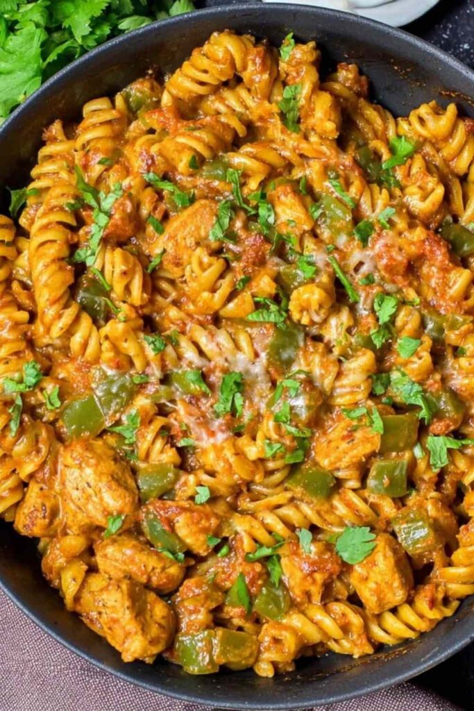 High protein chicken fajita pasta in a skillet with colorful bell peppers and creamy Greek yogurt sauce
