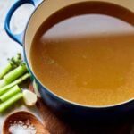 Homemade chicken broth simmering in a large stockpot with whole chickens and vegetables
