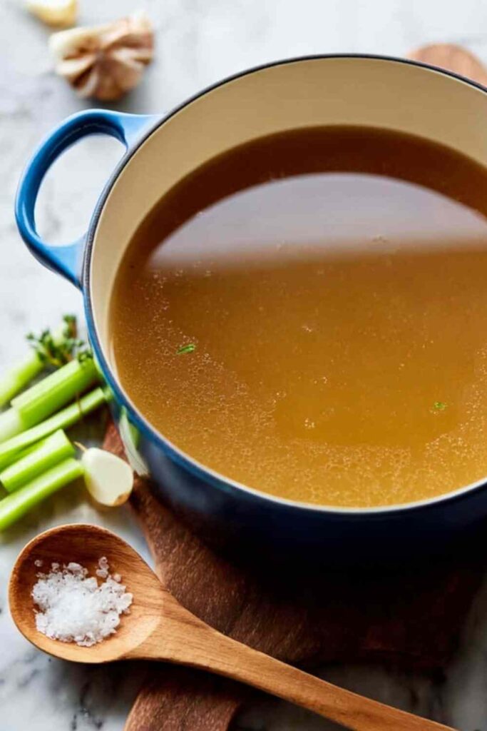 Homemade chicken broth simmering in a large stockpot with whole chickens and vegetables