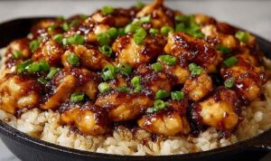Honey BBQ chicken rice recipe in a skillet garnished with fresh green onions