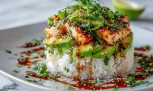 Honey Lime Chicken Avocado Rice Stack Honey lime chicken avocado rice stack on a white plate topped with fresh cilantro and lime dressing
