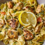 Lemon chicken pasta with mini farfalle, sliced golden seared chicken, zucchini, yellow squash, and freshly grated parmesan in a skillet