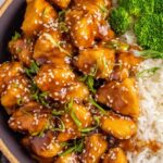 Mandarin chicken recipe in a skillet with glossy orange sauce coating golden browned chicken breast cubes