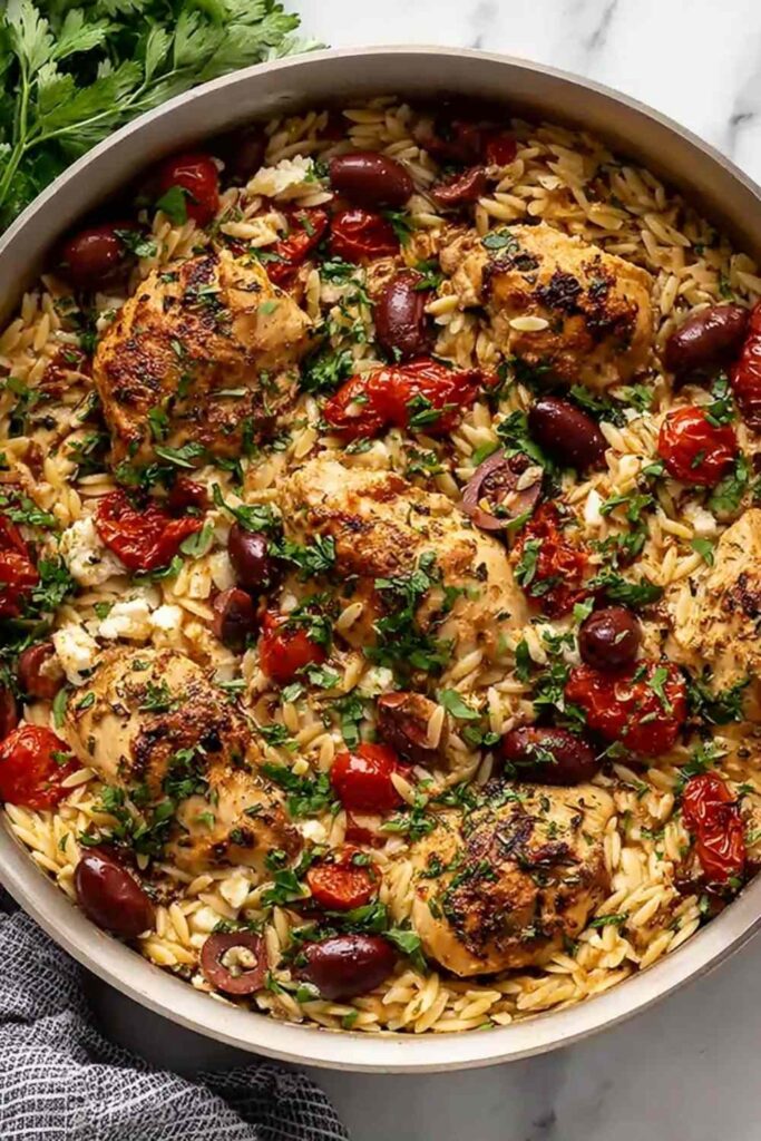One-pot Mediterranean chicken orzo with cherry tomatoes, kalamata olives, and crumbled feta cheese in a Dutch oven