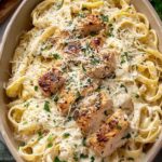 Olive Garden fettuccine Alfredo copycat recipe with crispy double-breaded chicken over creamy Alfredo sauce on a white dinner plate