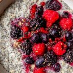 Overnight oats with mixed berries in a glass mason jar topped with fresh strawberries and blueberries