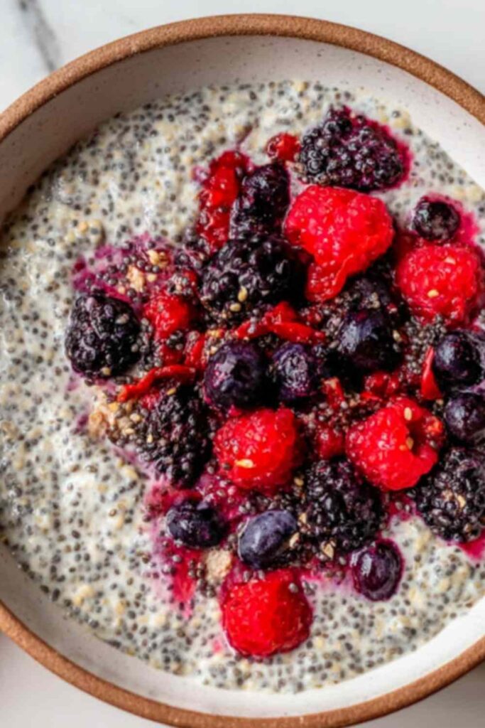 Overnight oats with mixed berries in a glass mason jar topped with fresh strawberries and blueberries