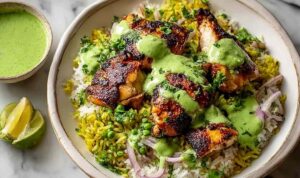 Peruvian Chicken and Rice with Green Sauce Peruvian chicken and rice with green sauce served in a bowl with sliced avocado and fresh lime wedges