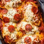 Pepperoni pizza stuffed chicken bake in a white 9x13 dish with golden melted mozzarella and bubbling marinara sauce