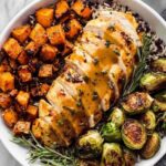Maple Dijon chicken sheet pan dinner with crispy Brussels sprouts and roasted sweet potato on a large rimmed baking sheet