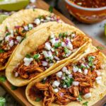 Shredded chicken tacos in warm corn tortillas with avocado, salsa, and cilantro
