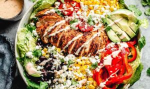 Southwest chicken salad with taco-seasoned chicken, avocado, black beans, corn, and chili lime dressing in a large bowl