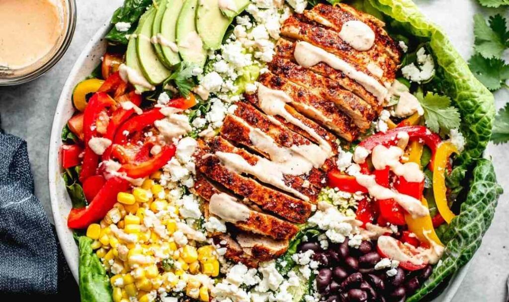 Southwest chicken salad with taco-seasoned chicken, avocado, black beans, corn, and chili lime dressing in a large bowl
